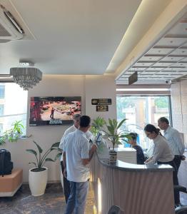 a group of people standing around a bar in a restaurant at Hotel Meridian in Jagādhri
