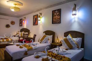 ein Hotelzimmer mit drei Betten mit Schwänen darauf in der Unterkunft RIAD HIKAYA - Born of History in Fès