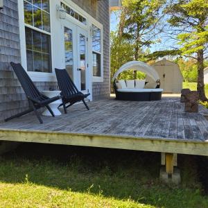 two chairs sitting on a deck in front of a house at Brackley Beach Schoolhouse in Brackley Beach