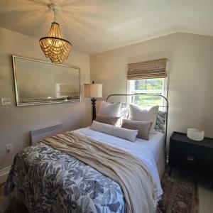 a bedroom with a bed with pillows and a chandelier at Brackley Beach Schoolhouse in Brackley Beach