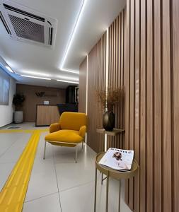 a living room with a yellow chair and a table at Studio Moderno Westfit - Barreto in Mossoró