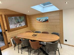 a dining room with a wooden table and chairs at Nid des aiguillettes in Chevenoz