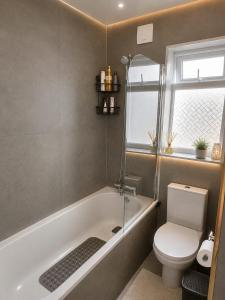 a bathroom with a bath tub and a toilet at Elegant Double Room in Nottingham