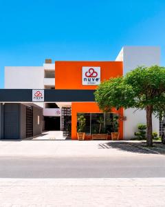 ein orange-weißes Gebäude mit einem Baum davor in der Unterkunft Nuve Express Corregidora in Torreón