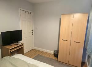 a bedroom with a bed and a dresser with a television at Elegant Double Room in Nottingham