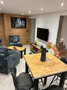 a living room with a table and chairs and a television at Nid des aiguillettes in Chevenoz