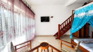 a living room with a staircase and a tv at Studio Cannelle - À deux pas de la plage Nosy Be in Nosy Be