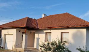 a white house with a brown roof at Veszei Apartman in Békéscsaba