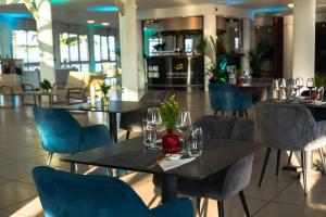 a dining room with tables and blue chairs at Hotel des Roches in Kourou