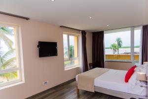 a bedroom with a bed and a tv and windows at Hotel des Roches in Kourou +85 photos