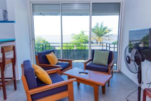a living room with chairs and a table and a balcony at Hotel des Roches in Kourou