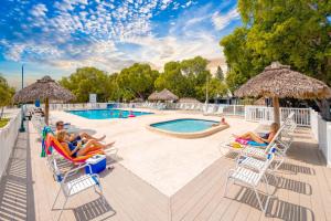 a group of people sitting in chairs by a pool at Key Largo Tiny House, Marina, Beach, and Pool Access in Key Largo