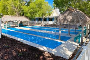 a blue swimming pool with a straw umbrella at Key Largo Tiny House, Marina, Beach, and Pool Access in Key Largo