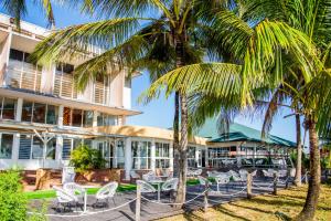 a resort with chairs and palm trees in front of it at Hotel des Roches in Kourou