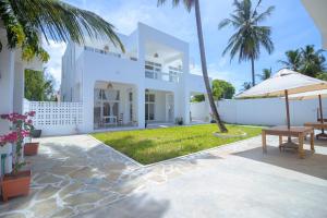an exterior view of a white house with palm trees at Lilo House in Watamu