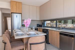 a kitchen with a table with chairs and pink flowers at Esprit Villas in Polis Chrysochous