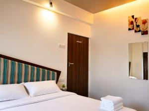 a bedroom with a bed and a wooden door at The Alibag Beach hotel- Grantley in Alībāg +16 photos
