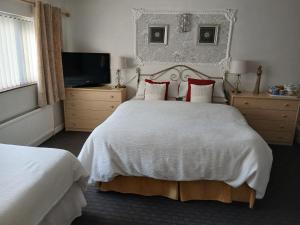 a bedroom with a large white bed and a television at Heskin Farm in Burscough