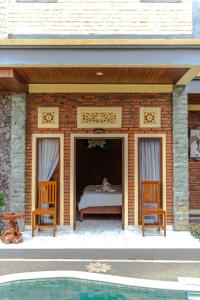 a patio with a bed and two chairs and a pool at The Garuda Villa and Restaurant in Bedugul