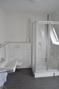 een witte badkamer met een douche en een wastafel bij Hotel Haus Thoeren in Kerken