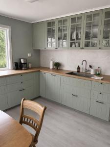 a kitchen with white cabinets and a table and a sink at Hovstø Hytter & Rom in Seljord