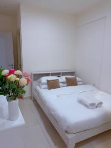 a white bedroom with a bed with a vase of flowers at Minique stay - spacious 3BR in Furena