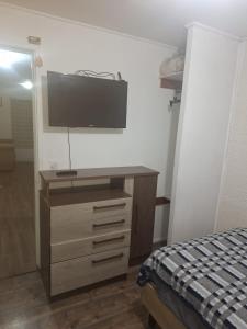 a bedroom with a dresser with a television on the wall at Casa agustina 2 in Valdivia +4 photos
