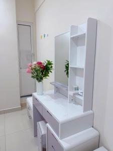 a white bathroom with a mirror and a vase of flowers at Minique stay - spacious 3BR in Furena