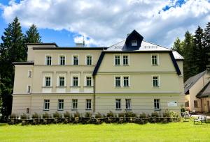 a large white building with a black roof at Hotel Natura Centrum Zdrowia in Duszniki Zdrój
