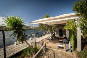 a house with people sitting on a deck next to the water at Douro View by Porto in Valbom