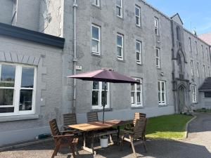 a wooden table with an umbrella in front of a building at IEC Campus for Groups in Kanturk