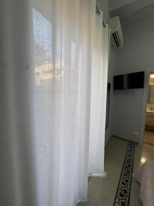 a white curtain in a room with a television at Scilla Central Rooms in Scilla