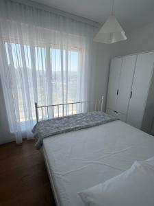 ein weißes Schlafzimmer mit einem Bett und einem großen Fenster in der Unterkunft Olive Nest in Mrčevac