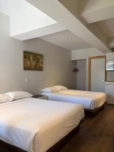 two beds in a room with white walls at Dragon Gate Inn in Toronto