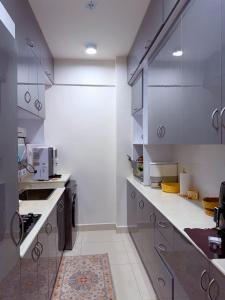 a large kitchen with white counters and appliances at Minique stay - spacious 3BR in Furena +15 photos