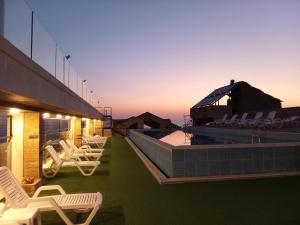 a patio with chairs and a swimming pool at sunset at Hotel Bouery in An Nā‘ūrah