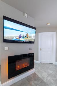 a living room with a flat screen tv above a fireplace at 18 Garden Mews in Cookstown