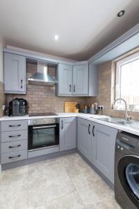 a kitchen with white cabinets and a sink and a dishwasher at 18 Garden Mews in Cookstown