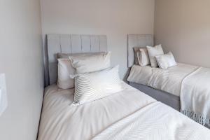 two beds in a room with white sheets and pillows at 18 Garden Mews in Cookstown