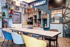 a table and chairs in a library with bookshelves at Hotel Kiel-Schwedenkai in Kiel