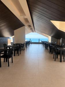 a dining room with tables and chairs and the ocean at Hotel Bouery in An Nā‘ūrah