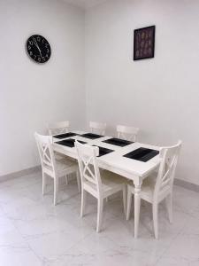 a white table with chairs and a clock on a wall at CB Apartment in Santeo
