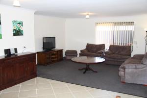 a living room with couches and a tv and a table at Byford House on the Scarp in Armadale