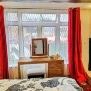 a bedroom with red curtains and a desk and a mirror at Cornerstone Budget in Ashford