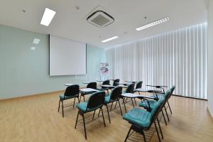 a classroom with tables and chairs and a whiteboard at POP! Hotel Timoho Yogyakarta in Yogyakarta