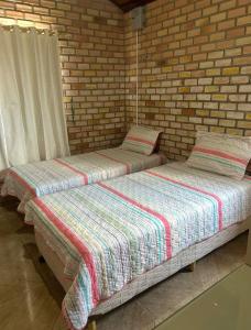 two beds in a room with a brick wall at Estação Serrana in Pedro II