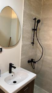 a bathroom with a sink and a shower with a mirror at Zahra Elegant Studio in Sīdī ‘Abd ar Raḩmān