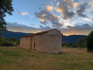 an old stone building in a field with a sunset at La Toscana en Lozoya in Alameda del Valle