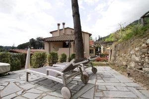 un patio de piedra con un banco y una casa en Giuliana en Camaiore