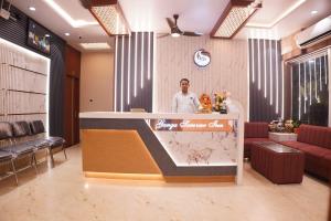 a man standing behind a counter in a lobby at Hotel ganga sarovar Inn in Deoghar